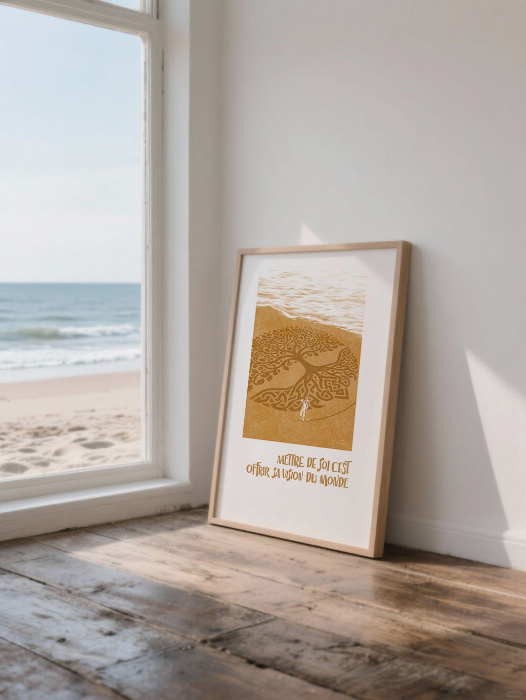 Affiche “Mettre de soi, c’est offrir sa vision du monde” appuyée contre un mur blanc près d’une grande fenêtre donnant sur la plage.