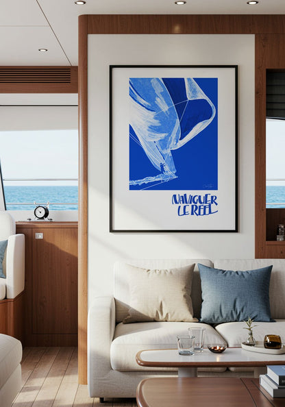 Affiche bleue “Naviguer le réel” accrochée dans l’intérieur d’un yacht moderne, décoré de bois et textile clair.