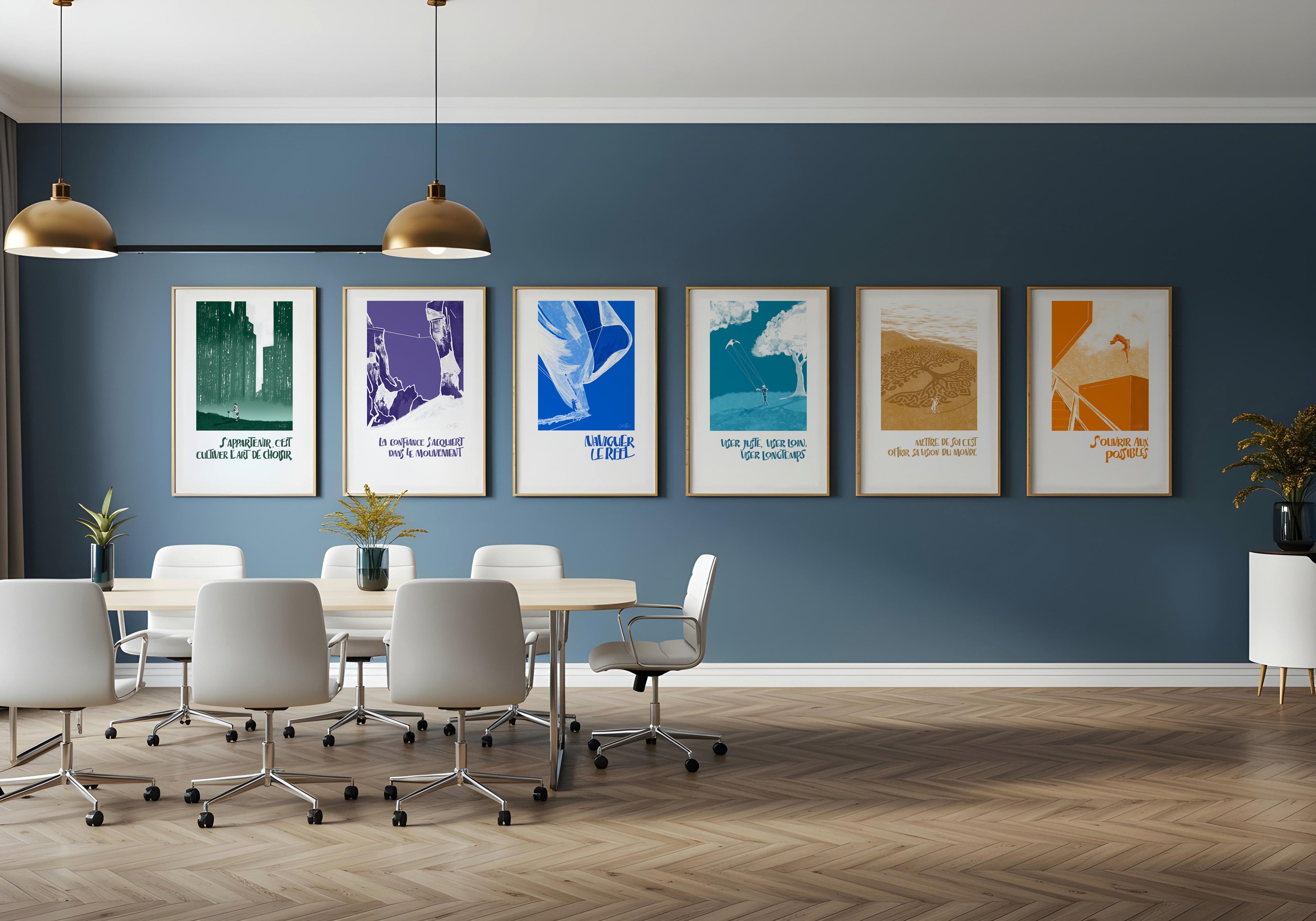 Mur de six affiches colorées encadrées dans une salle de réunion moderne avec chaises blanches et suspension dorée.